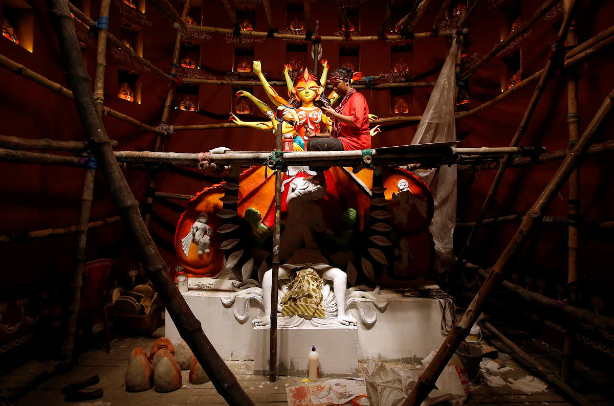Artist Upashona Chatterjee checks her mobile phone as she decorates an idol of the Hindu goddess Durga at a pandal, or a temporary platform, for the upcoming Hindu festival of Durga Puja in Kolkata. (Reuters Photo)