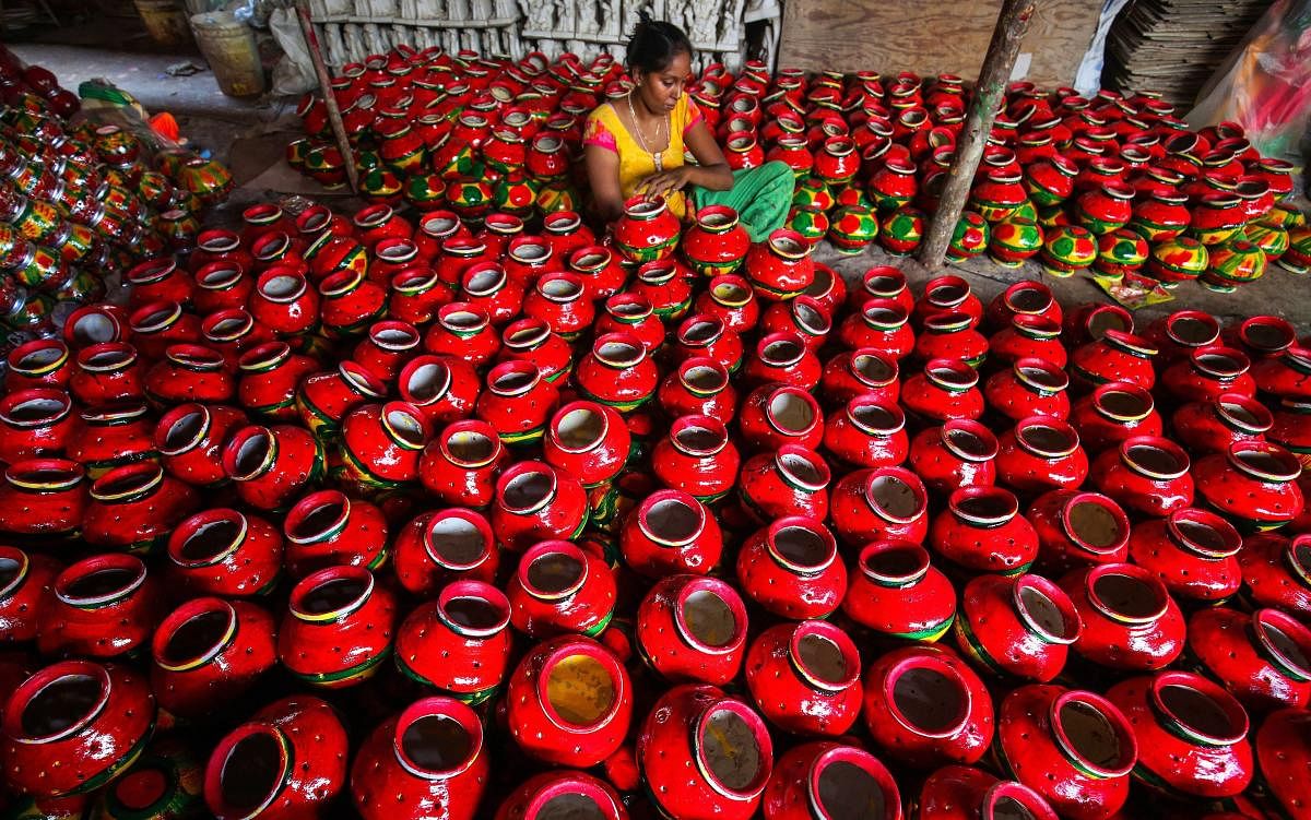 An artisan decorates earthern pitchers used during Gujarati folk dance 'Garba', ahead of Navratri festival, in Ahmedabad. (PTI Photo)