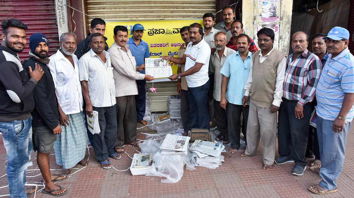 Newspaper agents release all pages colour edition of Deccan Herald and Prajavani, near Devaraja Market in Mysuru on Friday. DH photo