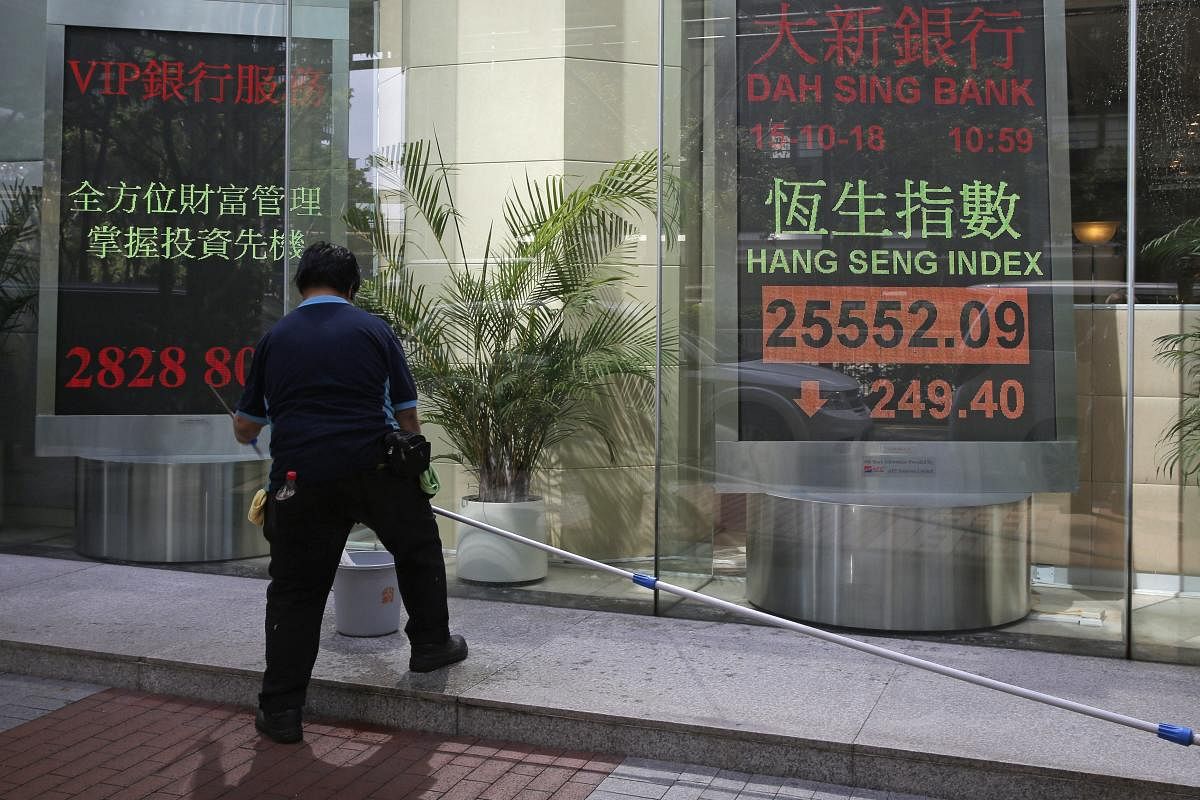 A worker stands in front of an electronic board showing Hong Kong share index outside a bank In Hong Kong. Asian stocks slipped Monday, as investor worries continued about global trade tensions and prospects for economic growth. AP/PTI