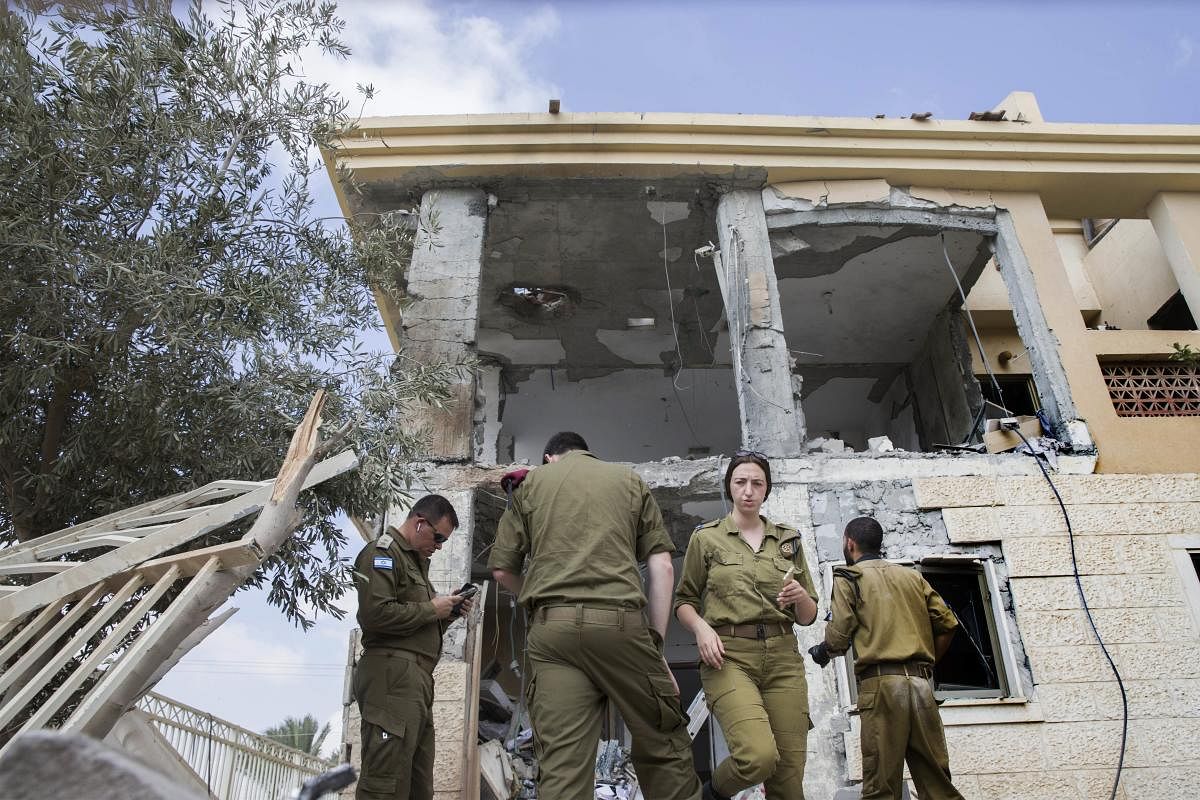 Israeli soldiers stand in front of a house that was hit by a missile fired from Gaza Strip, in the city of Beersheba, southern Israel. A medical service said a woman and her three children, whose home was struck, were being treated for shock after they fled to their shelter upon being awoken by warning sirens. AP/PTI