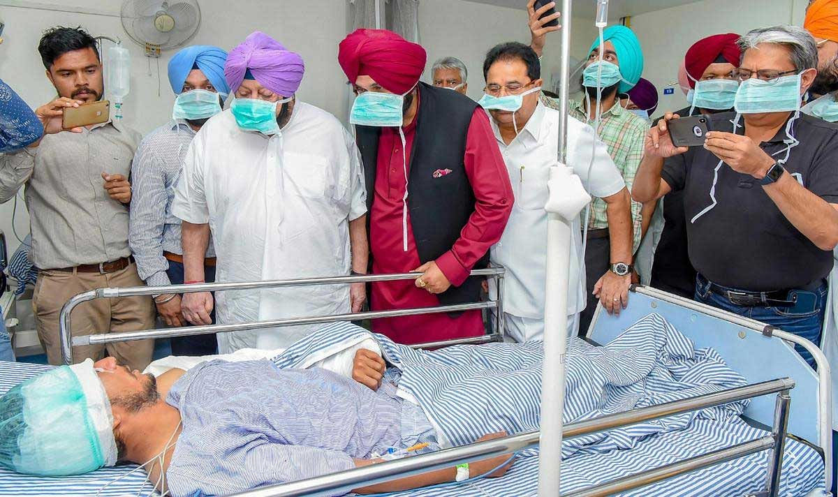 Punjab Chief Minister Capt Amarinder Singh with Punjab Minister Navjot Singh Sidhu visit a victim of the train accident at Jodh Phatak, at Civil Hospital in Amritsar, Saturday, Oct 20, 2018. A speeding train ran over revellers watching fireworks during the Dussehra festival yesterday, killing at least 60 people. PTI Photo