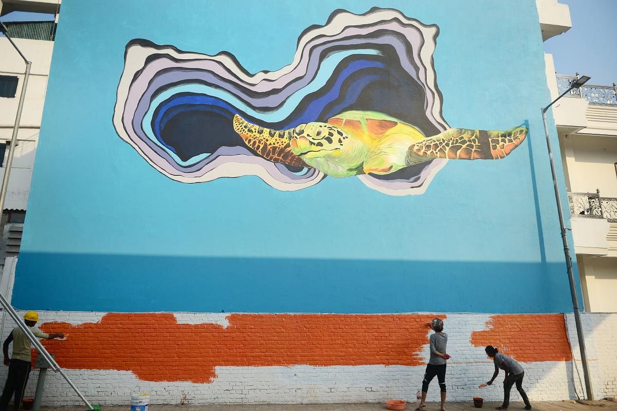 Indian artists paint a wall of a building as part of an ongoing project 'Paint my City' in Allahabad on October 27, 2018. (Photo by SANJAY KANOJIA / AFP)