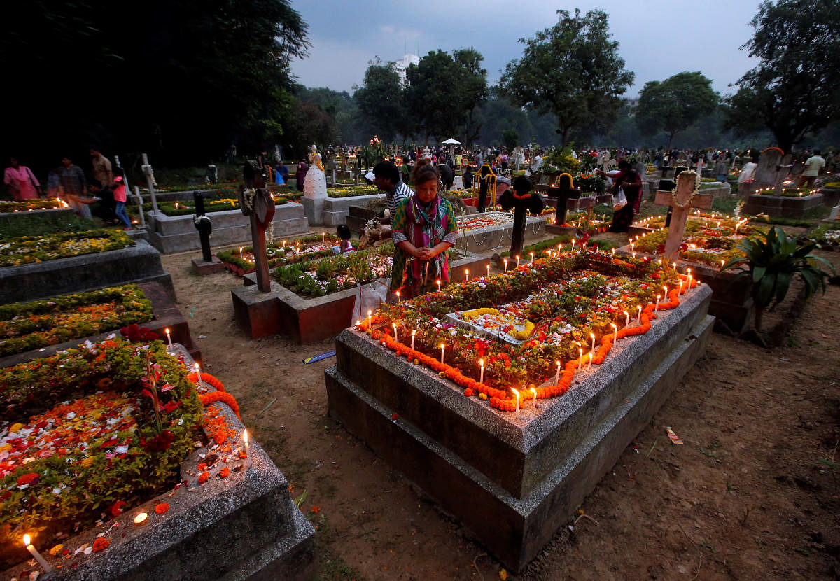 People pray after lighting candles on the grave of their relatives at a cemetery during the observance of All Souls Day, in Kolkata, India, November 2, 2018. REUTERS