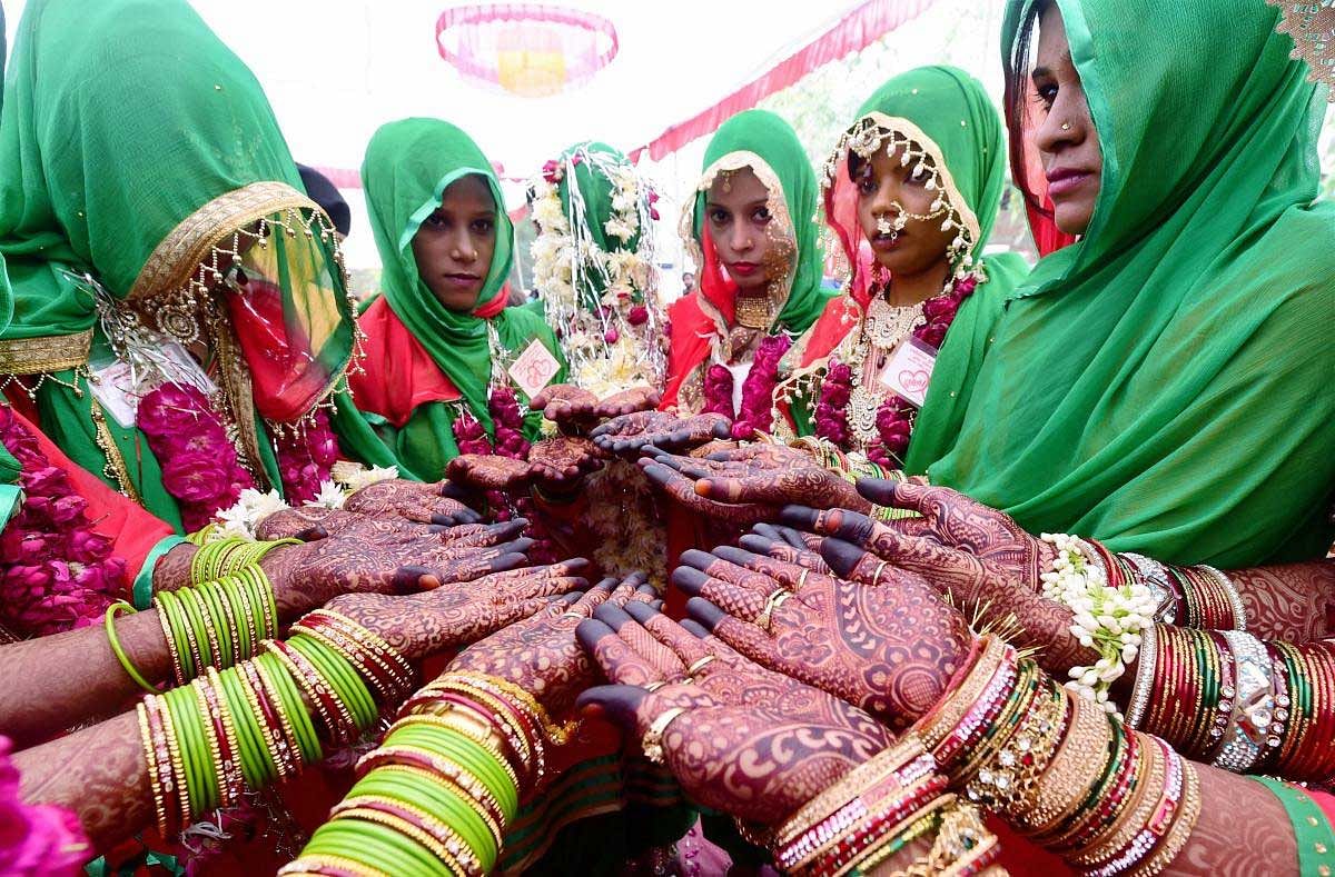 Brides pose for a photograph with their henna applied hands during a mass marriage ceremony in Ahmedabad on Sunday. November 4, 2018. (PTI Photo/Santosh Hirlekar)