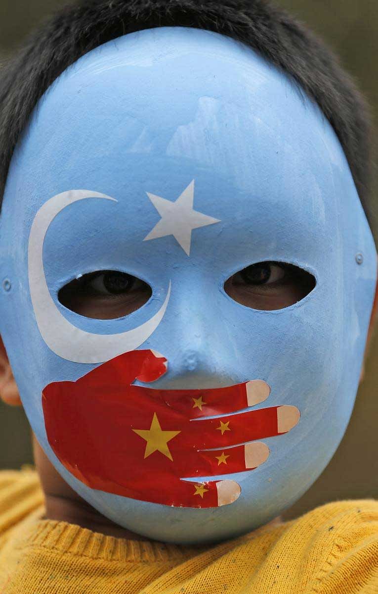 A child from the Uighur community living in Turkey wears a mask in the colours of the flag what ethnic Uighurs call 'East Turkestan', with a painted hand with the colours of China's flag, during a protest in Istanbul, Tuesday, Nov. 6, 2018, against what they allege is oppression by the Chinese government to Muslim Uighurs in the far-western Xinjiang province. AP/PTI