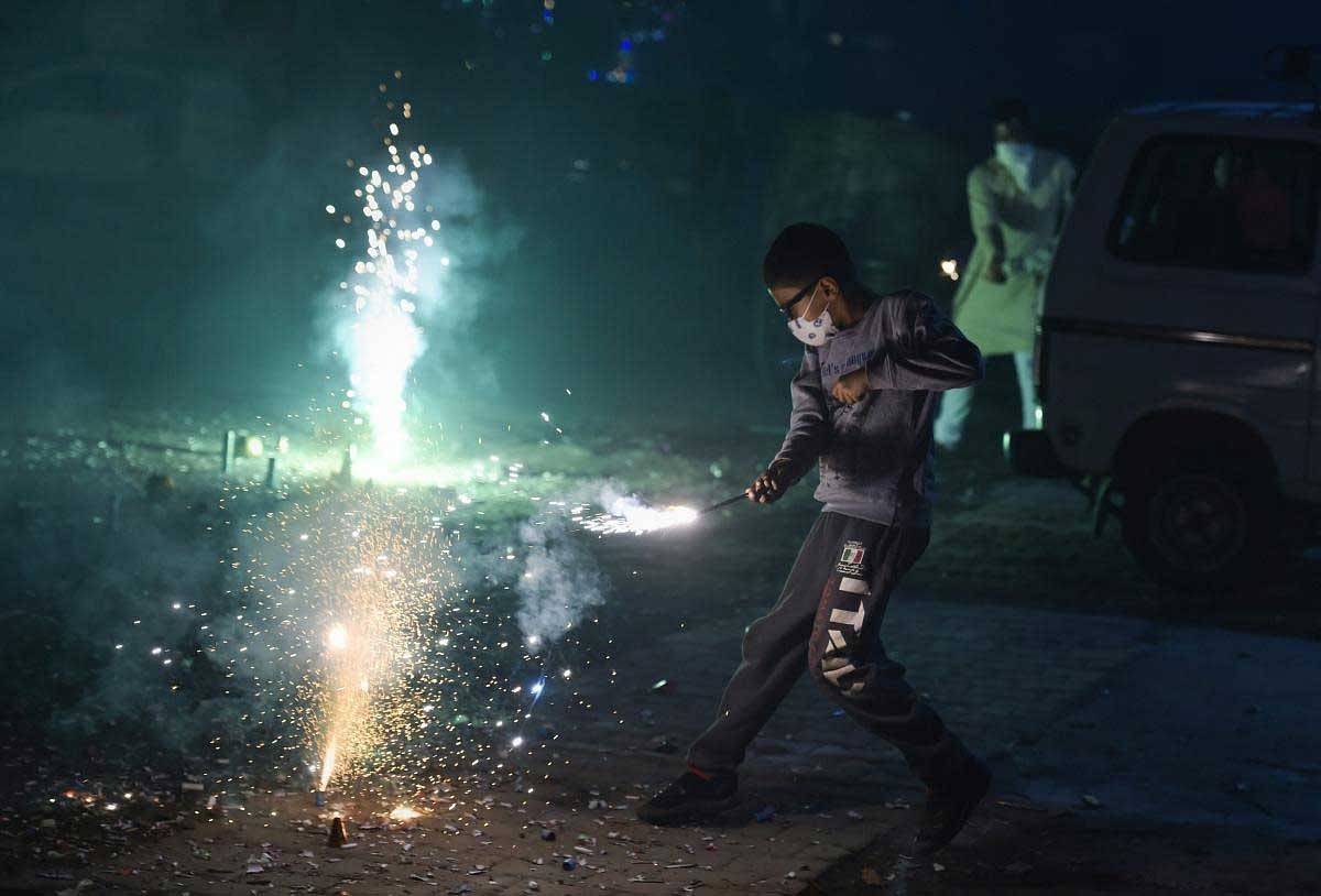 A boy wearing pollution mask burns crackers during Diwali celebrations, in New Delhi, Wednesday, Nov. 07, 2018. According to the officials, Delhi recorded its worst air quality of the year the morning after Diwali as the pollution level entered 'severe-plus emergency' category due to the rampant bursting of toxic firecrackers. (PTI Photo)