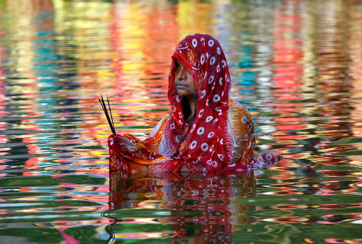 A Hindu woman worships the Sun god in the waters of a lake during the religious festival of Chhath Puja in Agartala, November 13, 2018. REUTERS