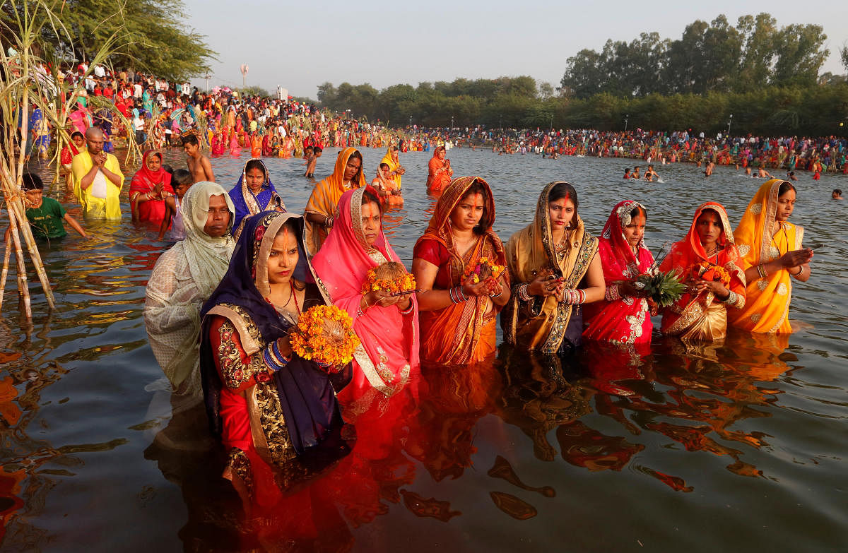 Hindu women hold offerings as they worship the Sun god in the waters of a lake during the Hindu religious festival of Chhath Puja in Chandigarh, November 13, 2018. REUTERS