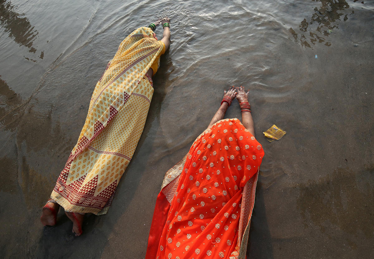 Hindu women lie as they worship the Sun god in the waters of the Arabian Sea during the religious festival of Chhath Puja in Mumbai, November 13, 2018. REUTERS