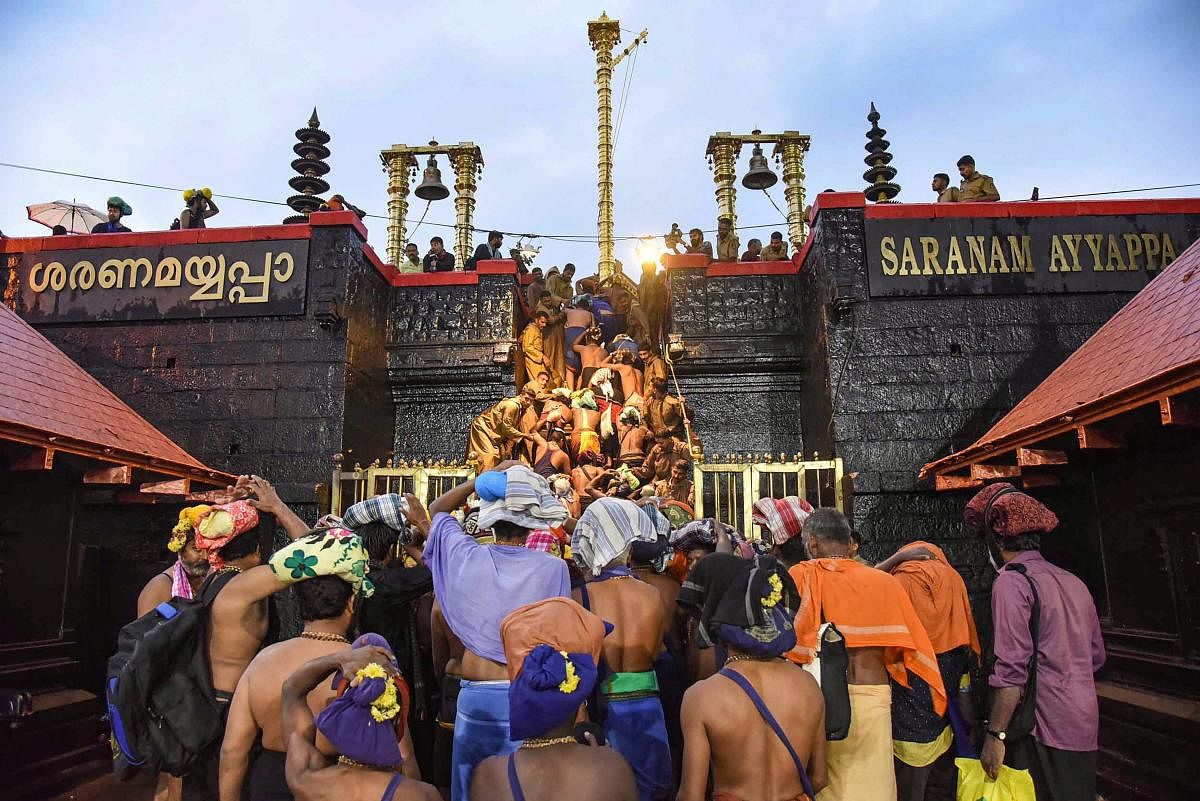 Devotees enter the Sabarimala temple as it opens amid tight security, in Sabarimala. PTI Photo