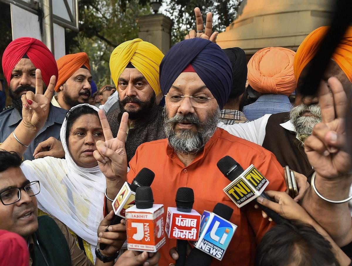 DSGPC Chief Manjeet Singh GK shows the victory sign while talking to the media outside the Patiala House Court in New Delhi.PTI Photo