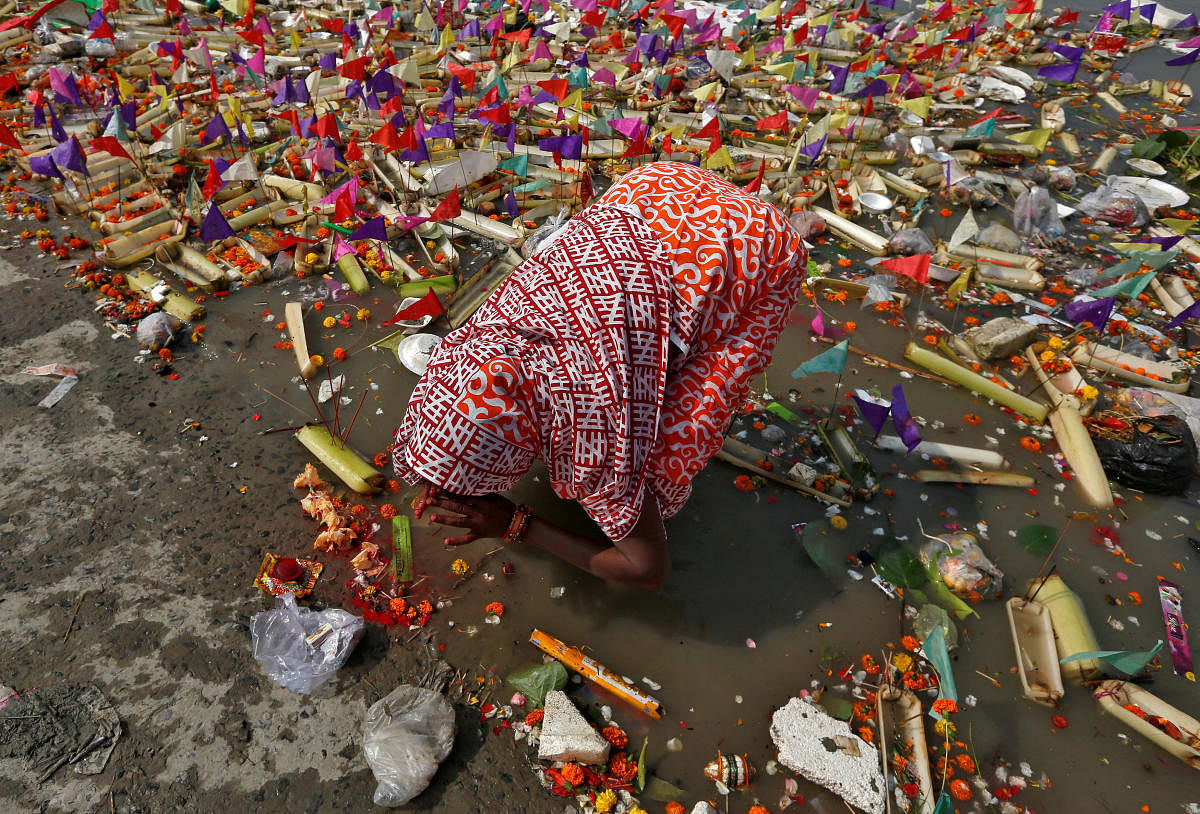 A woman worships after floating a small decorated boat made with banana stem in the waters of the Ganga river on the occasion of the annual Hindu festival of