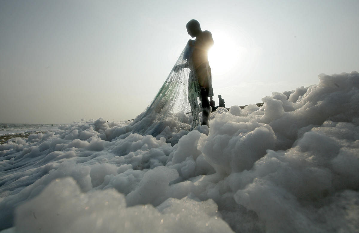 A fisherman pulls his net on the shore filled with foam at the Marina beach in Chennai, India, November 23, 2018. REUTERS/P. Ravikumar TPX IMAGES OF THE DAY