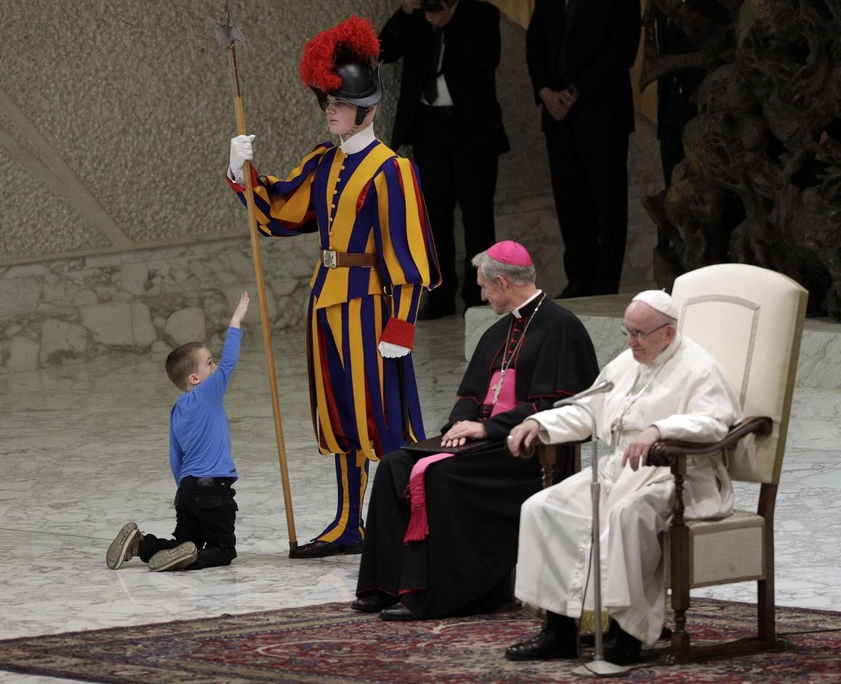Vatican City: A child plays with a Swiss guard in the Paul VI Hall at the Vatican, Wednesday, Nov. 28, 2018. Pope Francis has praised the freedom, albeit undisciplined, of a hearing impaired child who climbed onto the stage during his general audience to play. The Swiss Guards and Vatican gendarmes stood by Wednesday and gamely let the young boy run around Francis as monsignors read out his catechism lesson in various languages in the Vatican audience hall. AP/PTI