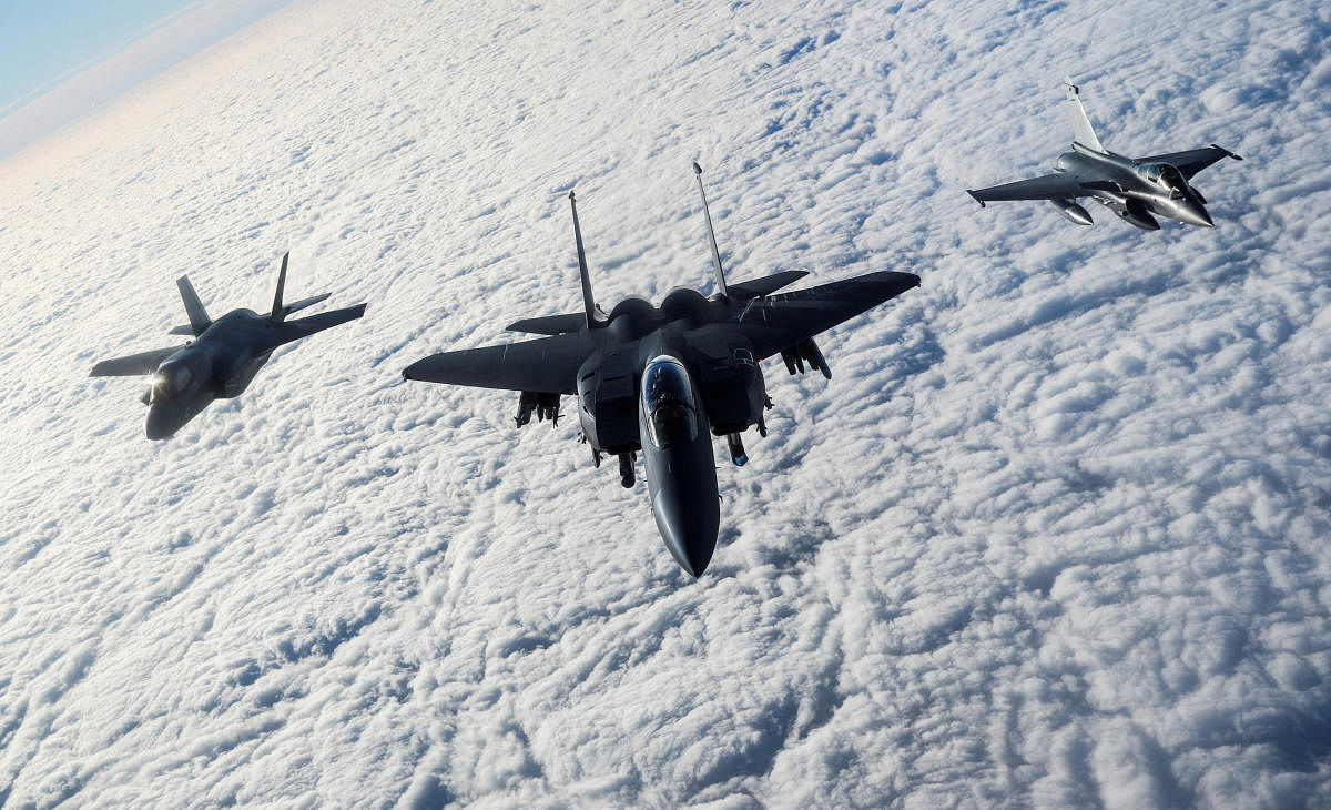 An RAF F-35B Lightning, a USAF F-15E Strike Eagle and a French Rafale fly over The English Channel in formation during the