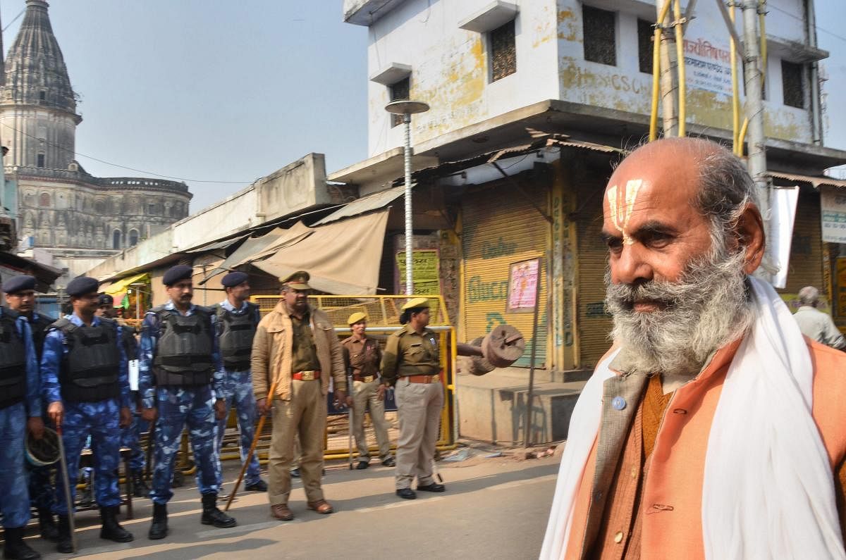 A sadhu walks along a road as police and RAF personnel keep vigil, on the anniversary of Babri mosque demolition, in Ayodhya. (PTI Photo)