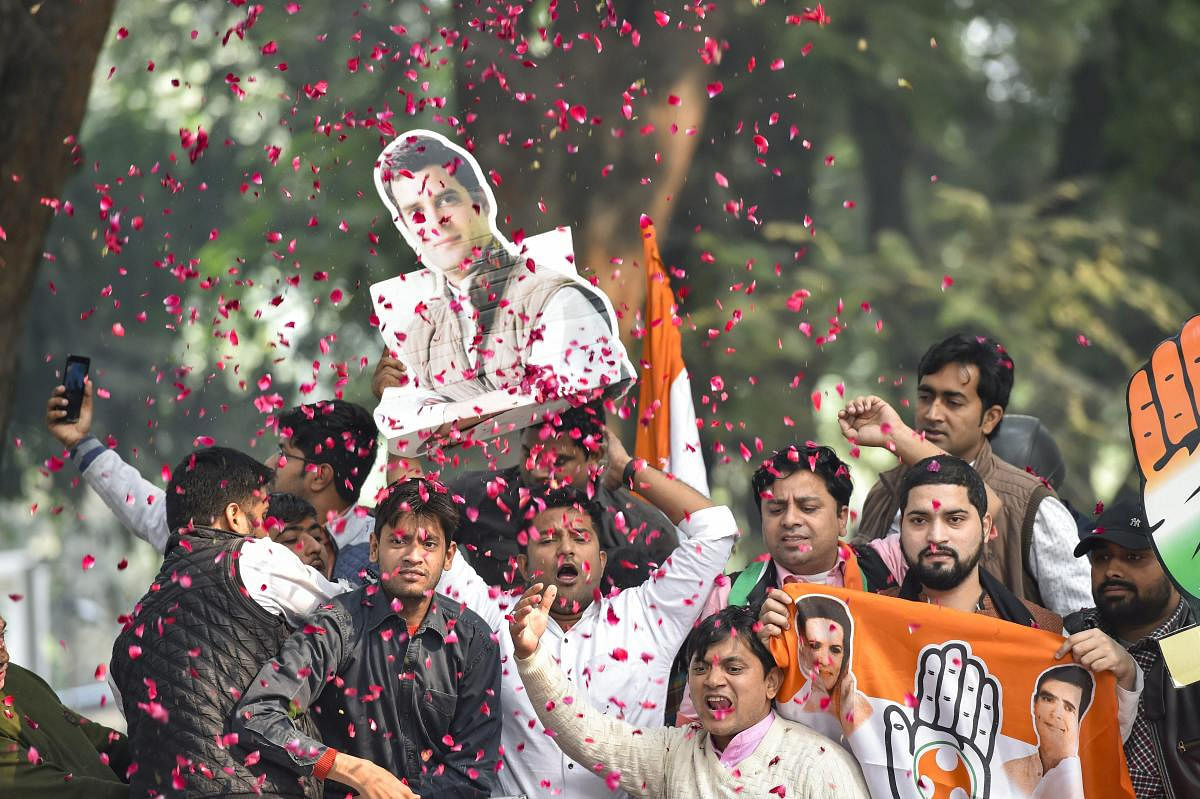 Congress Party workers display Congress President Rahul Gandhi's cutout as they celebrate after initial trends showed the party leading in the state Assembly election results, at the Congress headquarters in New Delhi, Tuesday, Dec.11, 2018. (PTI Photo)