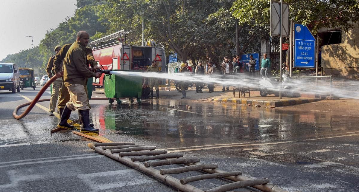 Firemen atwork after an oil tanker spilled oil on the road in Chankyapuri, New Delhi. PTI photo