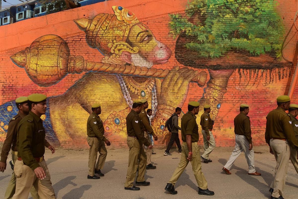 Policemen walk past a wall painted with a picture of Lord Hanuman during 'Nagar Pravesh' procession of Panch Dashnam Atal Akhara sadhus for the Kumbh Mela 2019, in Allahabad on December 13.