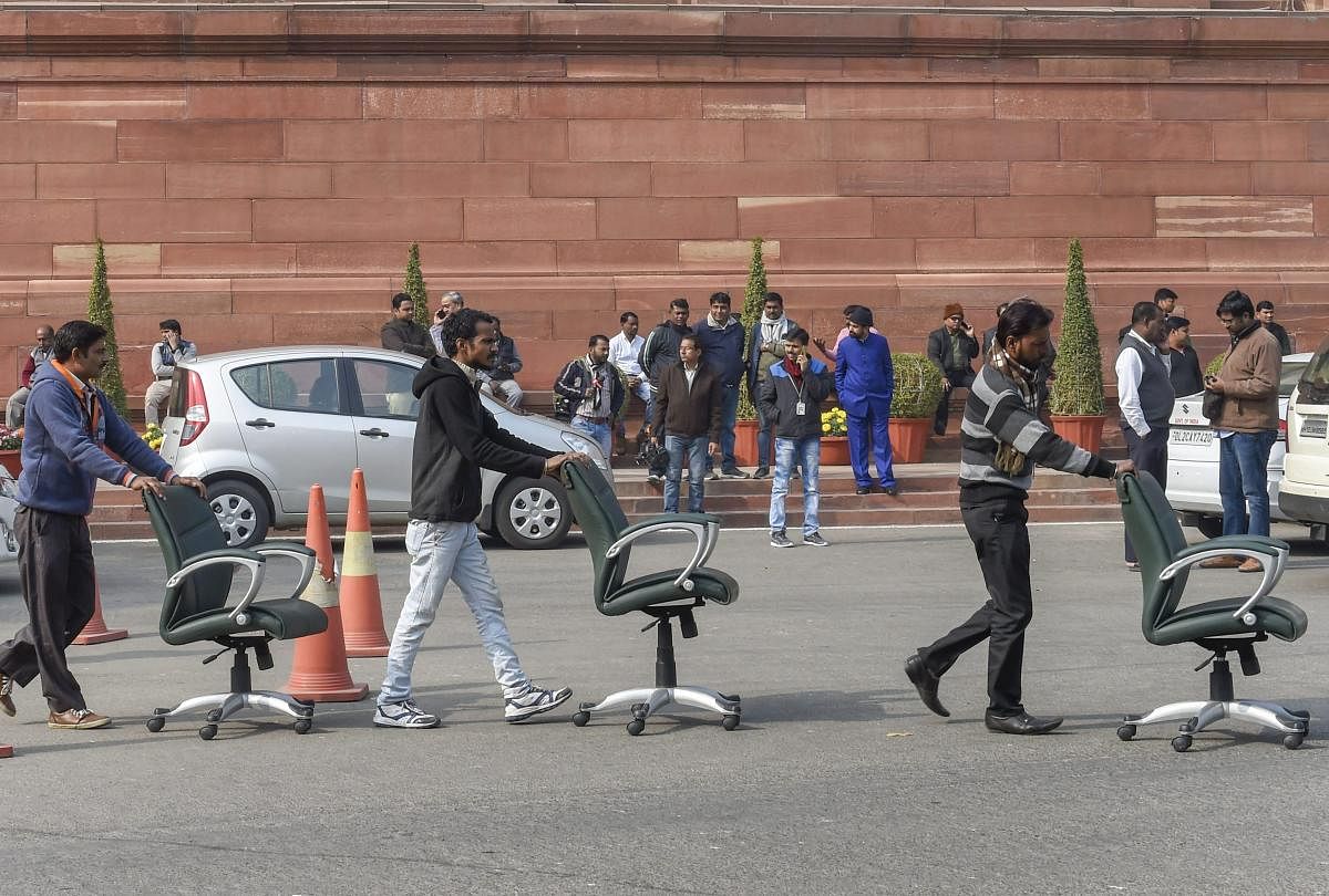 Workers move wheeled chairs at Parliament House, in New Delhi. PTI