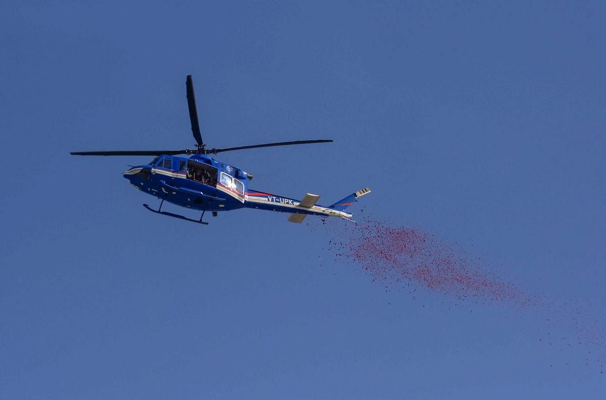 A helicopter sprays flowers on Naga Sadhus who are taking holy dip the on auspicious Makar Sankranti day during the Kumbh Mela in Allahabad (Prayagraj). PTI photo