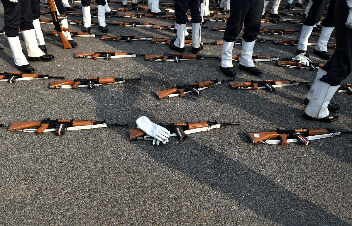 Guns and gloves are placed, foreground, as Airforce soldiers take a break during the rehearsal for the upcoming Republic Day parade 2019 on a cold morning, at Rajpath in New Delhi. PTI photo