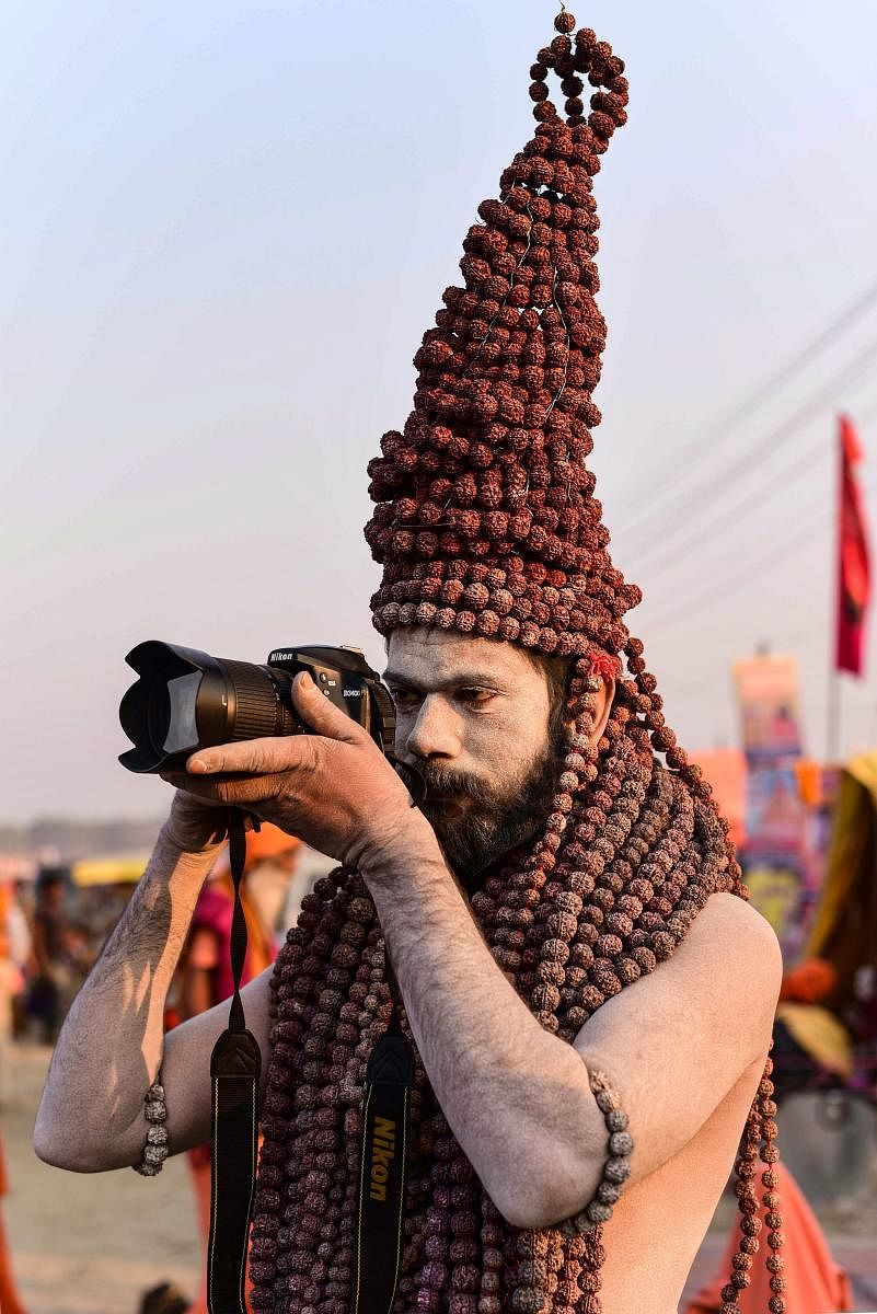 A Naga sadhu wears rudraksha garlands as she takes photo with a camera during Kumbh Mela festival 2019 in Allahabad. PTI photo