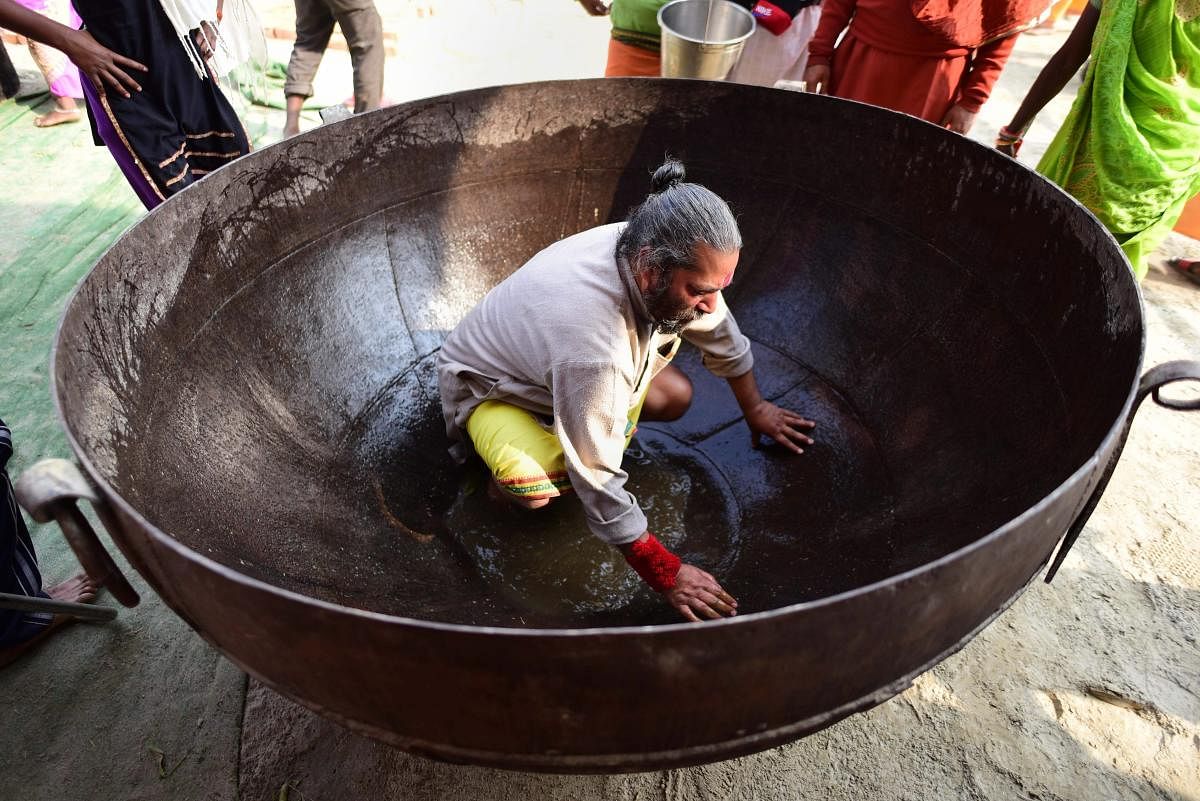 A man cleans a huge Kadahi (pan) to be used for cooking food for pilgrims at a camp during the ongoing Kumbh Mela 2019 festival in Allahabad. (PTI Photo)