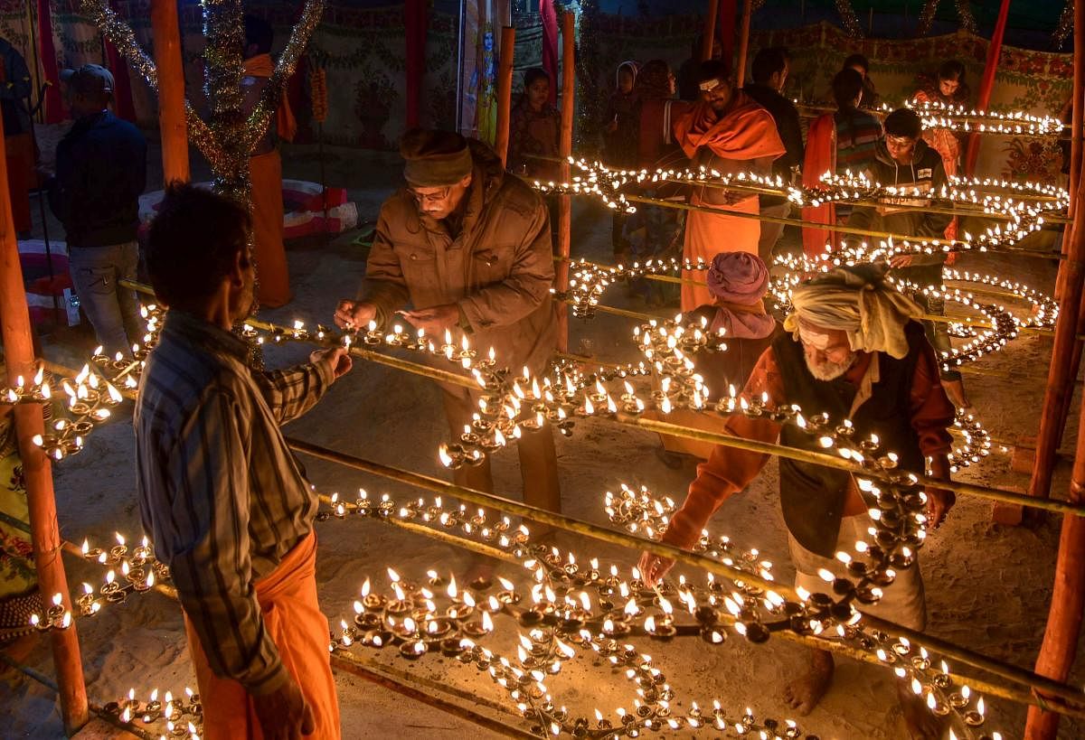 Sadhus along with devotees light oil lamps as a part of evening prayers during Kumbh Mela 2019 in Allahabad. (PTI Photo)