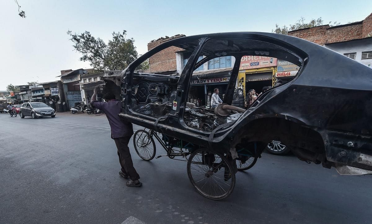 A rickshaw puller tows away a mangled car on a cycle rickshaw, in Ahmedabad, Thursday, Feb 7, 2019. (PTI Photo/Santosh Hirlekar)