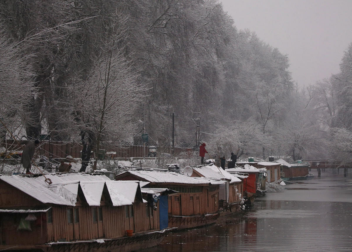 People remove snow from the roofs of their houseboat during a snowfall in Srinagar February 7, 2019. REUTERS/Danish Ismail