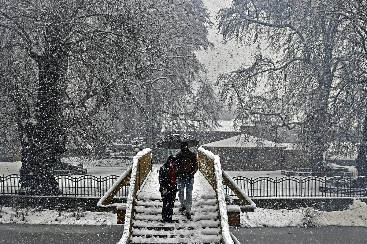 A tourist couple climb down a snow-covered staircase during heavy snowfall, in Srinagar, Thursday, Feb 7, 2019. Air traffic and highways were affected due to frequent snowfall and landslides since last two days. (PTI Photo/S Irfan)
