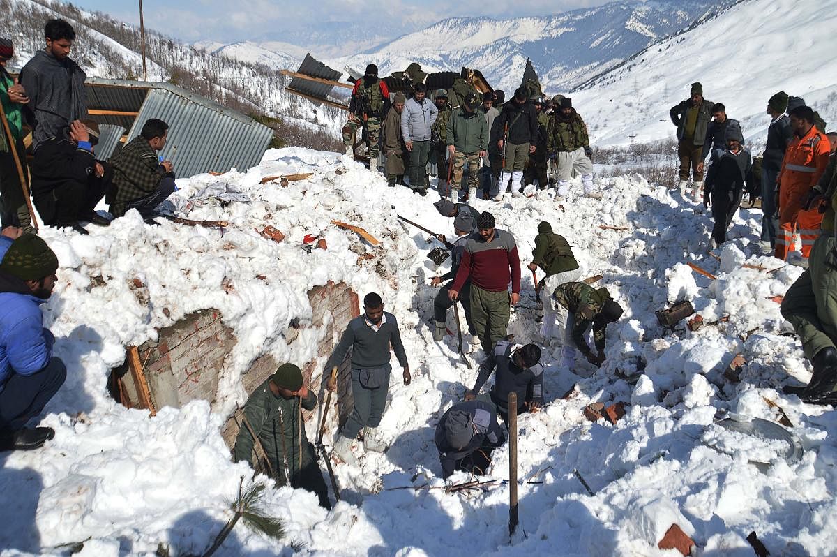 Local residents along with security personnel search the bodies of 10 missing policemen after a snow avalanche hit a police post at Qazigund Jawahar Tunnel in Kulgam district, some 90 km from Srinagar on February 8, 2019. - Three policemen were rescued on February 8 while five other bodies were recovered from an avalanche that buried 10 people in Indian-administered Kashmir following two days of heavy snowfall, police said. (Photo by STR / AFP)