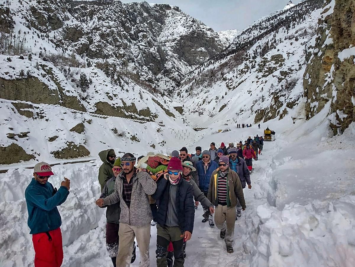 People walk on snow-covered road while carrying a patient to Stingri helipad for treatment, in Lahaul Spiti, Himachal Pradesh, Sunday, Feb 10, 2019. (PTI Photo)