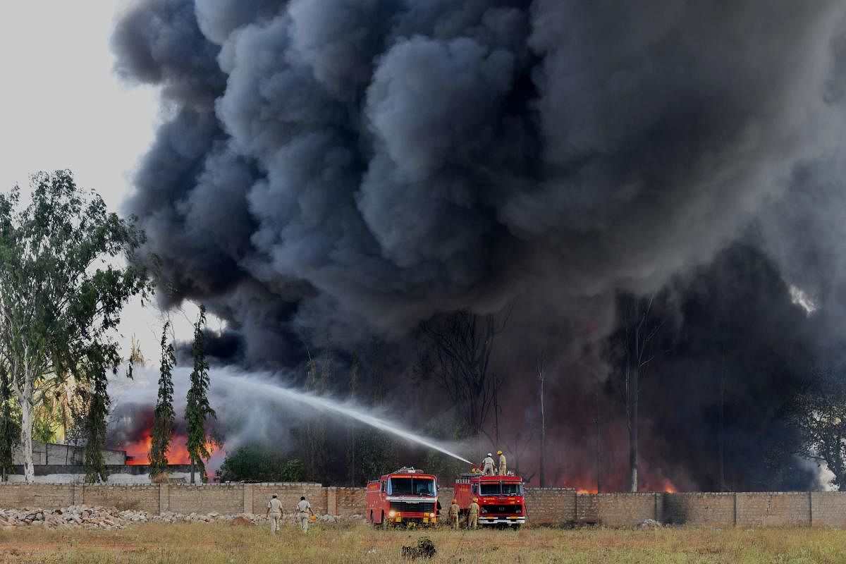 Firefighters battle a massive industrial fire on the grounds of a paint factory on the outskirts of Bangalore on February 13, 2019. - No casualties were reported in the blaze that ignited at the United Paints stockyard in Madanayakanahalli. (Photo by MANJUNATH KIRAN / AFP)