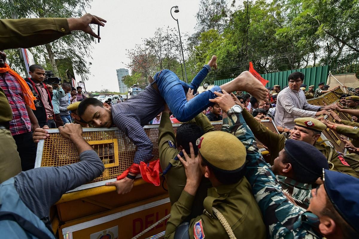 Delhi University Students Union (DUSU) and Akhil Bharatiya Vidyarthi Parishad (ABVP) members try to cross barricades during a protest march from ITO Metro Station to Delhi Secretariat demanding for better transportation facilities for students of off-campus colleges, in New Delhi, Monday, March 11, 2019. (PTI Photo/Arun Sharma)