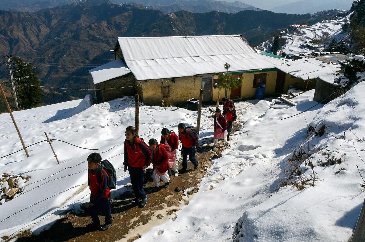 Students walk to school on a snow covered path after fresh snowfall at Kufri near Shimla. (PTI Photo)