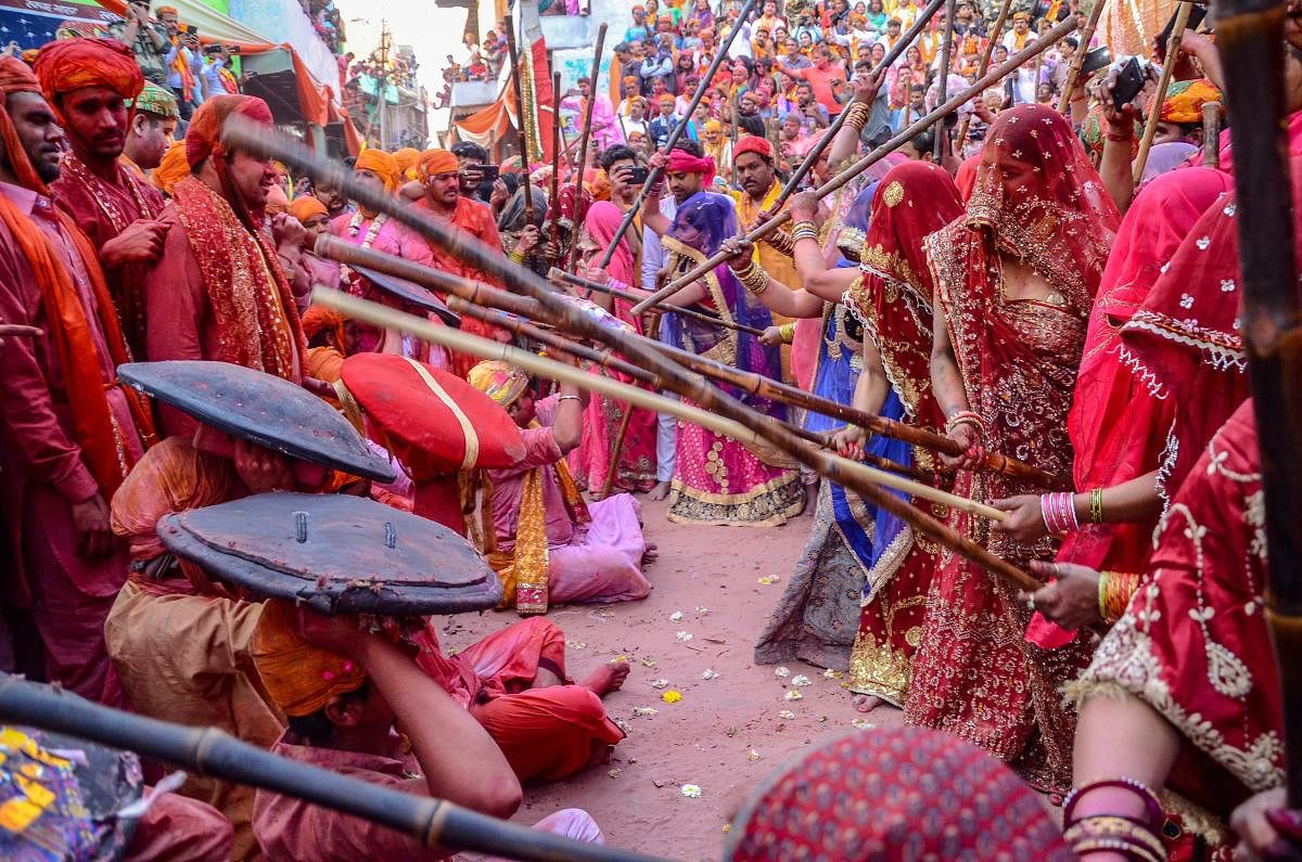 Women beat men with wooden sticks during the 'Lathmar Holi' festival in Barsana. (PTI Photo)