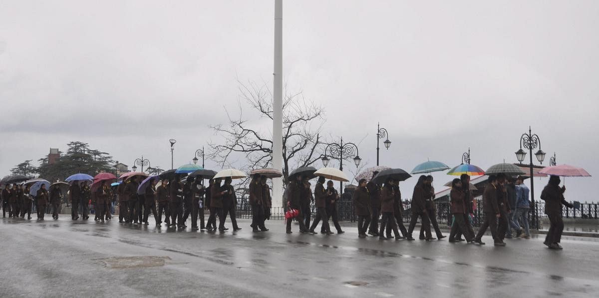 Pedestrians carry umbrellas during rains, at Ridge in Shimla, Thursday, March 14, 2019. (PTI Photo)