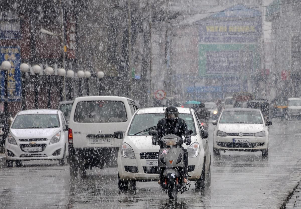 Vehicles drive through snowfall, in Srinagar. (PTI Photo)