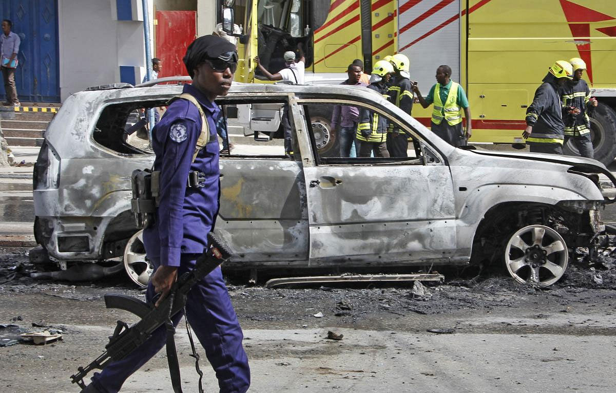 A member of security forces walks past the burned-out vehicle after a bomb planted in it exploded in Mogadishu, Somalia Tuesday, March 26, 2019. A Somali police officer says the bomb exploded killing the driver and injuring a nearby pedestrian in the Hodan district of the capital. AP/PTI