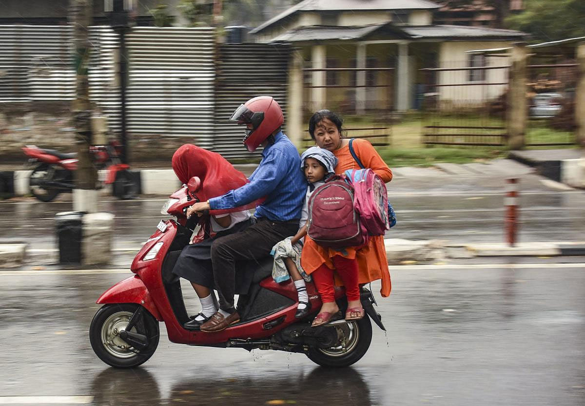 A family travels on a two-wheeler during rains in Guwahati, Tuesday, March 26, 2019. (PTI Photo)