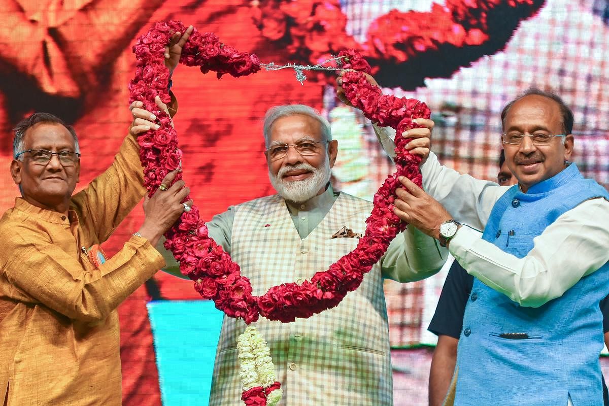 Prime Minister Narendra Modi being garlanded at 'Traders Sammelan' at Talkatora Stadium, in New Delhi, Friday, April 19, 2019. (PTI Photo/Kamal Kishore)