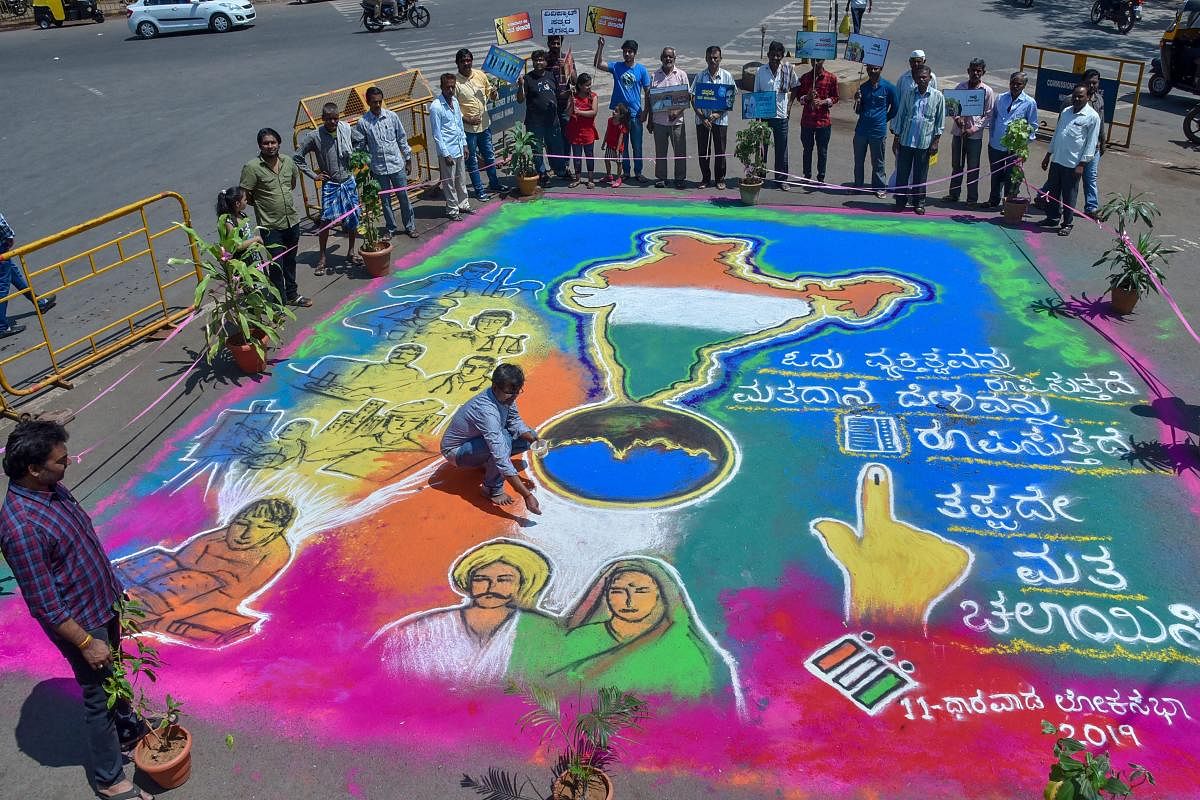 Visitors gather around a 'Rangoli' painted to create awareness among the voters ahead of the Lok Sabha elections, in Hubli, Sunday, April 21, 2019. (PTI Photo)
