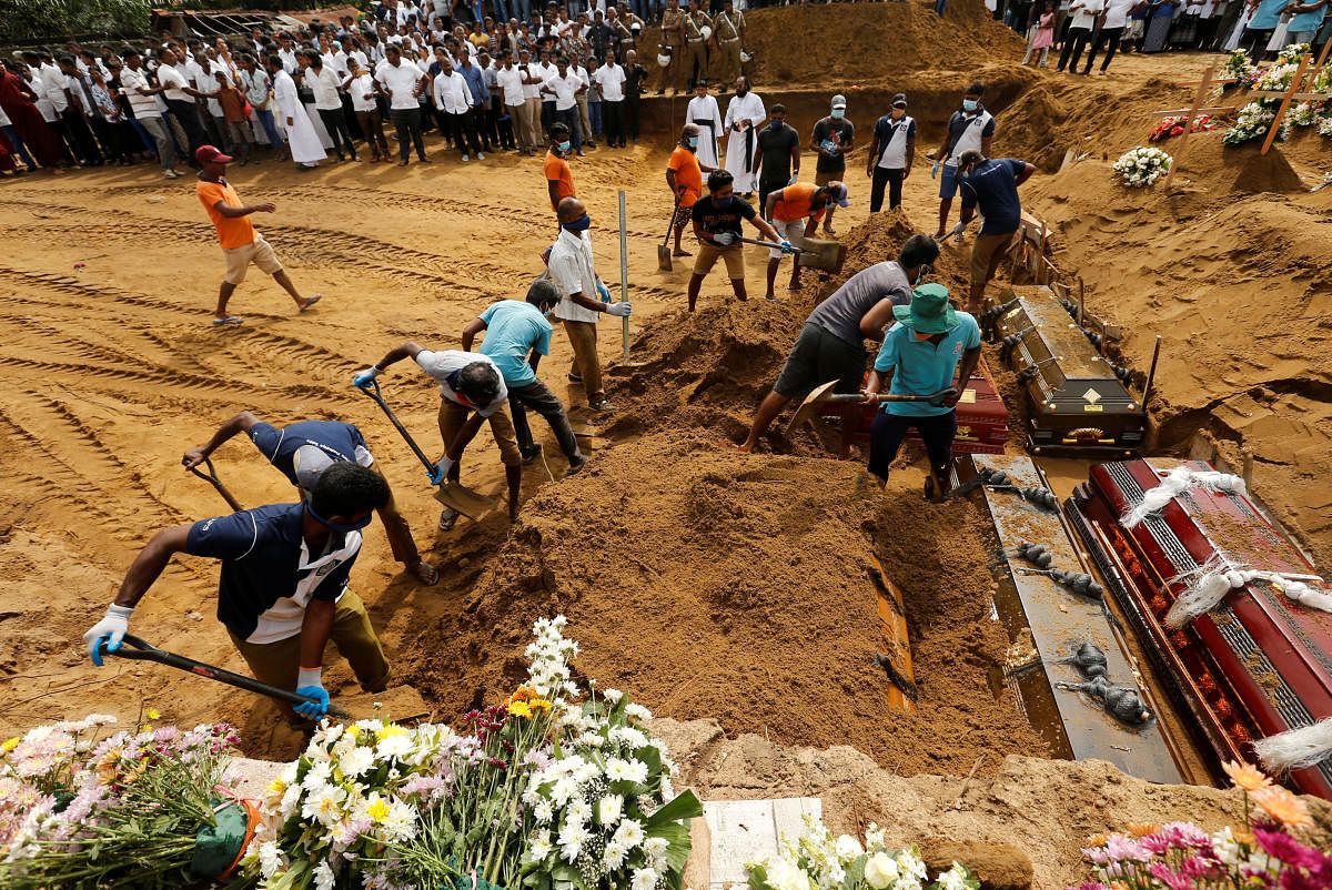 Coffins are laid in the ground during a mass burial for victims at a cemetery near St Sebastian's Church in Negombo, three days after a string of suicide bomb attacks on churches and luxury hotels across the island on Easter Sunday, in Sri Lanka April 24, 2019. REUTERS/Thomas Peter