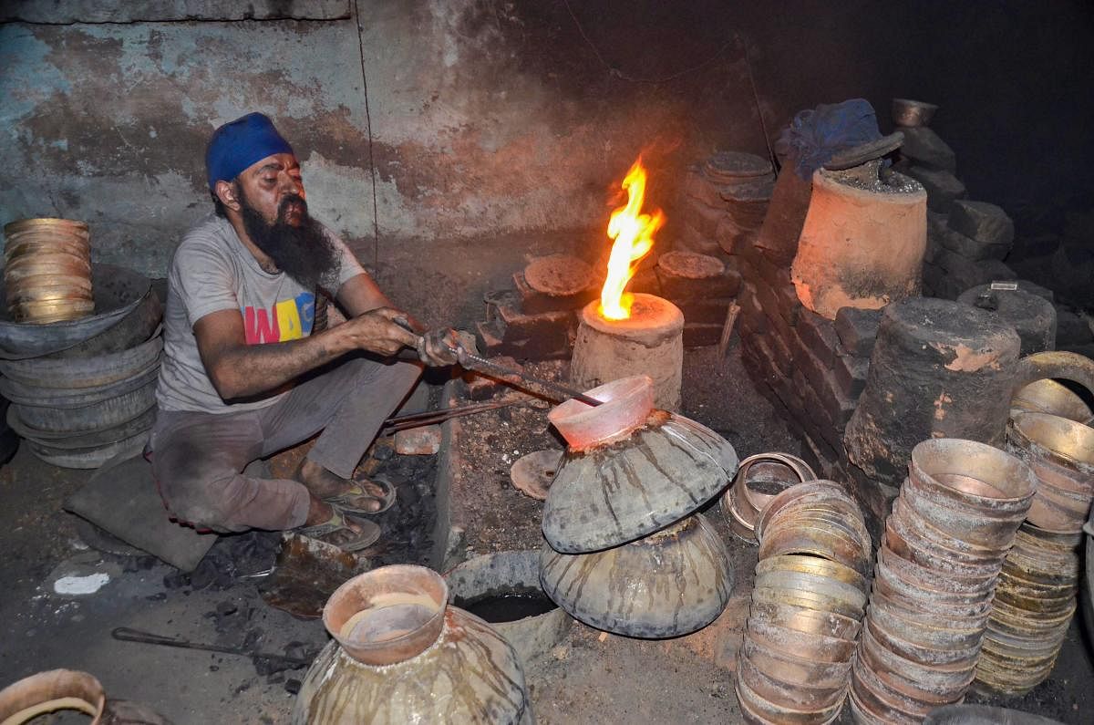 A worker moulds brass to make a utensil on International Labour Day, at a workshop in Mirzapur, Uttar Pradesh. (PTI Photo)