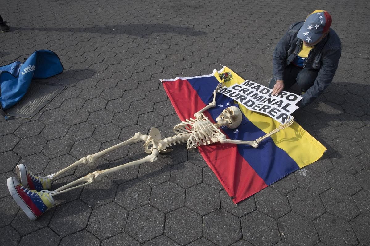A supporter of Venezuelan opposition leader Juan Guaido secures a skeleton to a Venezuelan flag during a rally in New York's Union Square. (AP/PTI Photo)