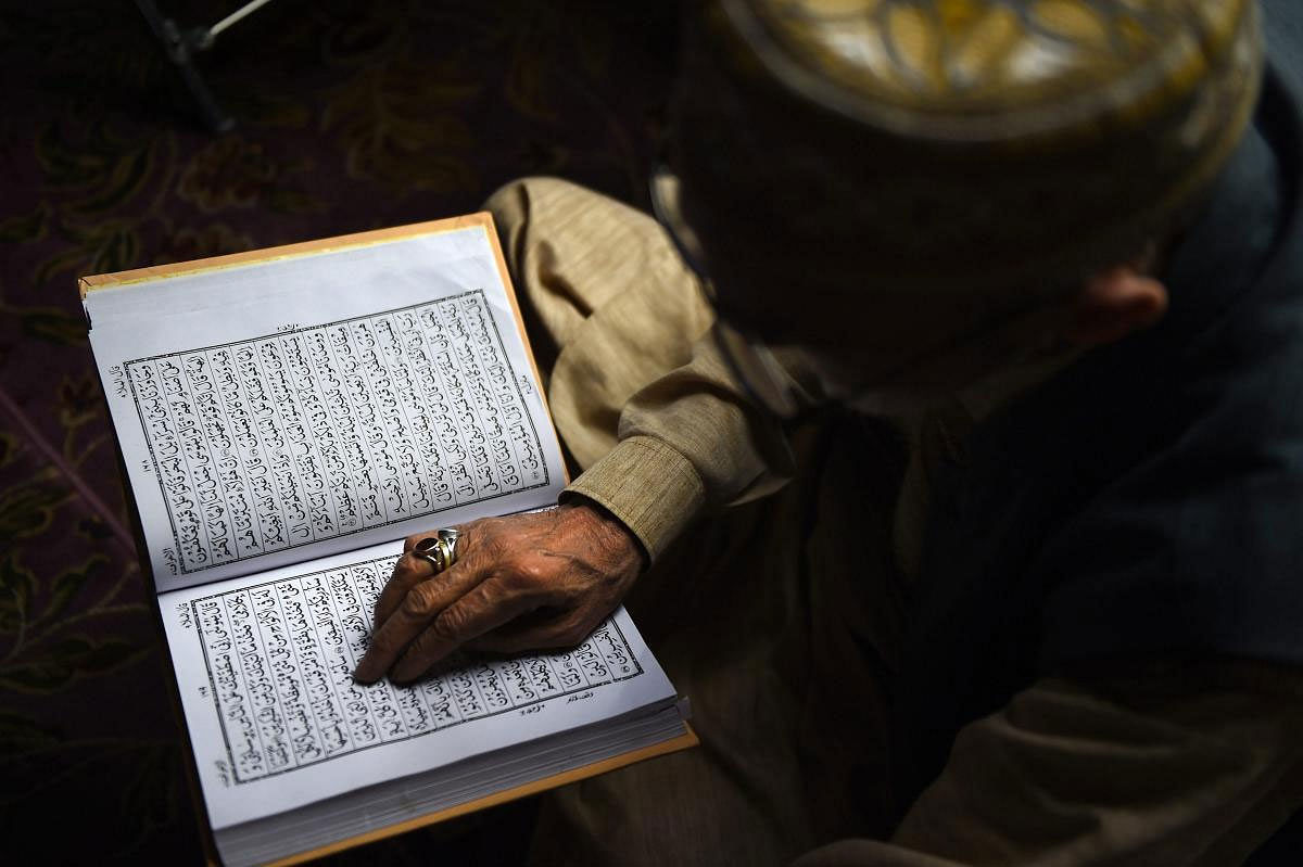 A Muslim devotee recites the holy book of Quran at a shrine on the third day of Ramadan month, in Srinagar, Thursday, May 9, 2019. (PTI Photo)