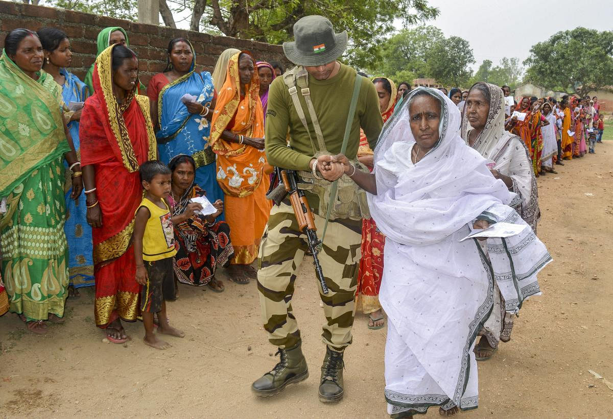A paramilitary jawan helps an aged woman at a polling booth during the sixth phase of Lok Sabha elections, in Purulia district of West Bengal, Sunday, May 12, 2019. (PTI Photo)